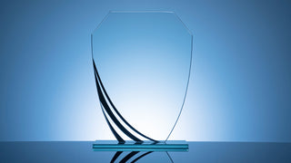 A uniquely shaped glass blank award sits on a blue background