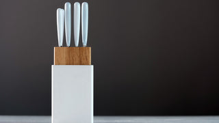 white knife handles stick out of a white and wooden knife block