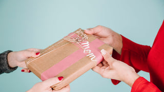 Daughter gifting her mother a package wrapped in brown paper with string