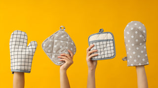 Two oven mitts and two pot holders being held up on a yellow background.