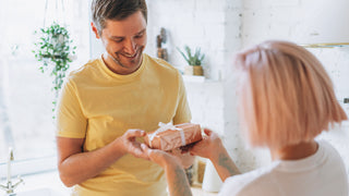 Man in yellow tshirt receives a gift from wife.