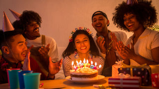 A group of friends gathers around a table to celebrate.