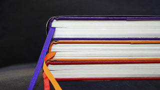 Stack of books in bright colours on a black background.