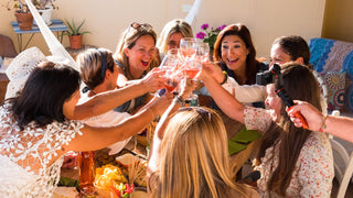 A group of women cheers their wine glasses at a celebration party.