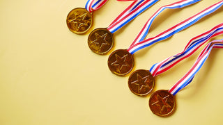 5 medals with blue, white and red ribbons sit on a yellow background.  The medals themselves are circular with gold facing and a large star in the middle.