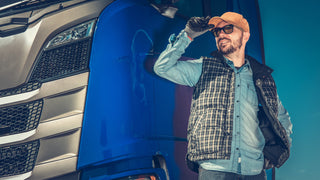 Man wearing an orange trucker hat stands beside his blue truck.