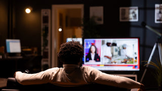 Man sits and watches a television program in his home.