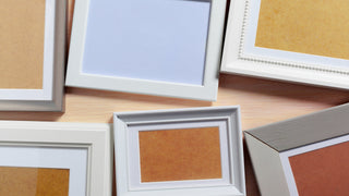 An assortment of empty picture frames in various beige and light blue colours with white frames.