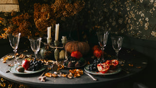 Spooky table decorated for Halloween with wine glasses, candles, plates and pumpkins