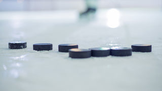 A small group of hockey pucks sitting on ice in a hockey rink.