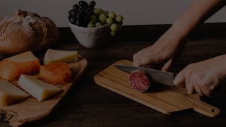 Cutting board on a chalkboard table with vegetables and fruit, and a cutting board with a custom engraving that says Meant to Brie