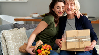 Daughter gifting her mother a package wrapped in brown paper with string