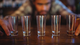 Bartender lining up shot glasses on the bar.  Tall shot glasses that can be engraved.