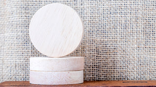 Round white coasters on a gingham background, sitting on a wooden table.