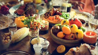 Full Table decorated with Thanksgiving wine glasses, flowers, food, and candles.