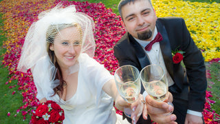 Couple celebrating their wedding with bright flowers in the background and having a toast with champagne flutes